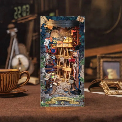 A completed model of a miniature world kit titled 'Magic Alley', featuring intricate details and a fantasy-themed setting, displayed on a table with a cup and frame in the background.